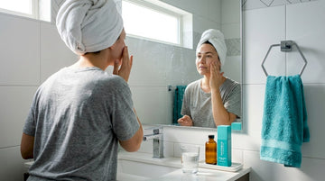 Woman applies moisturizer in morning bathroom routine